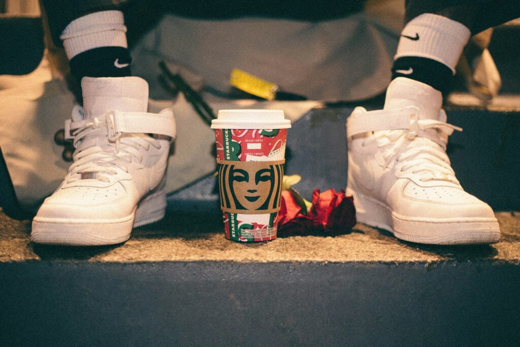 Par de tênis esportivos brancos ao lado de uma xícara de café, simbolizando a relação entre cafeína e prática esportiva