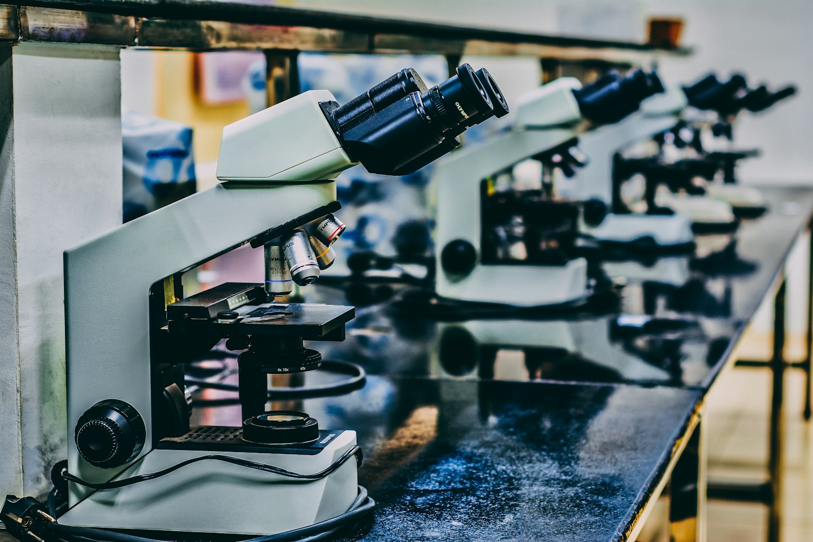 Microscópio branco sobre mesa preta em laboratório de pesquisa