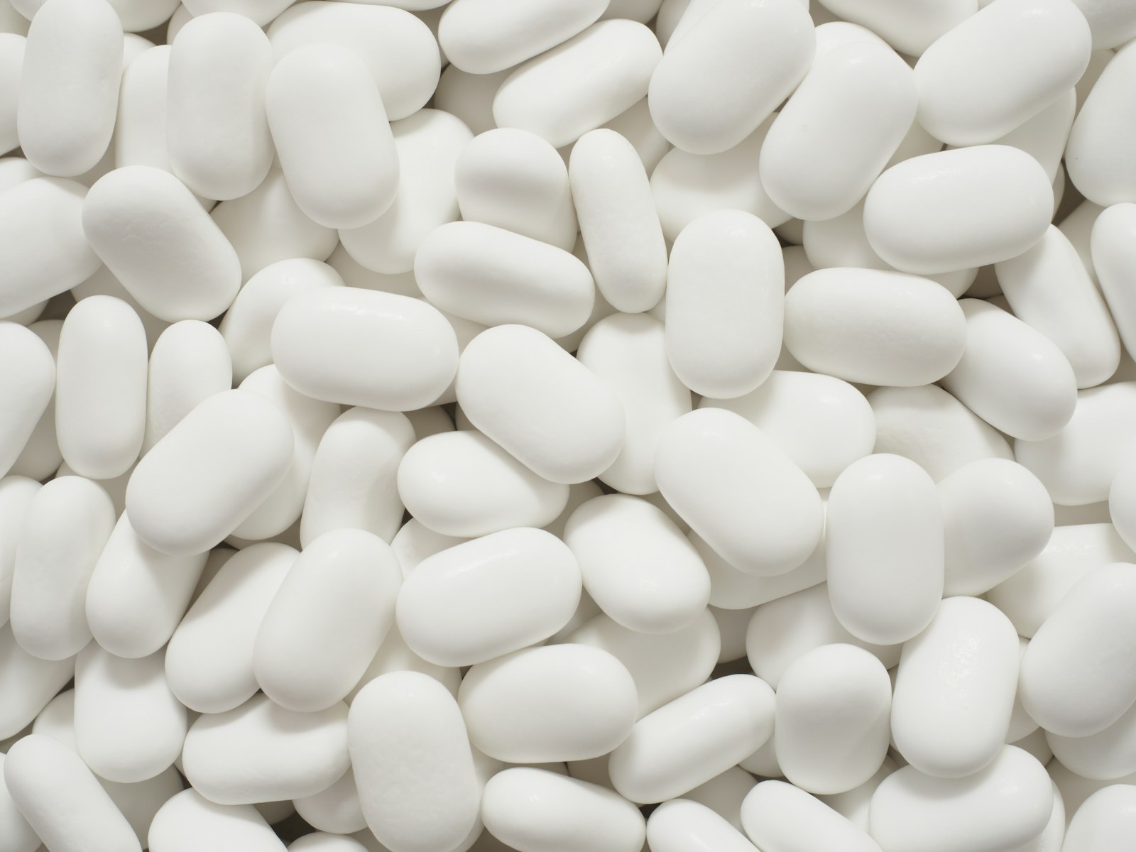 Diversos comprimidos brancos ovais, semelhantes aos usados em pílulas de placebo em estudos clínicos