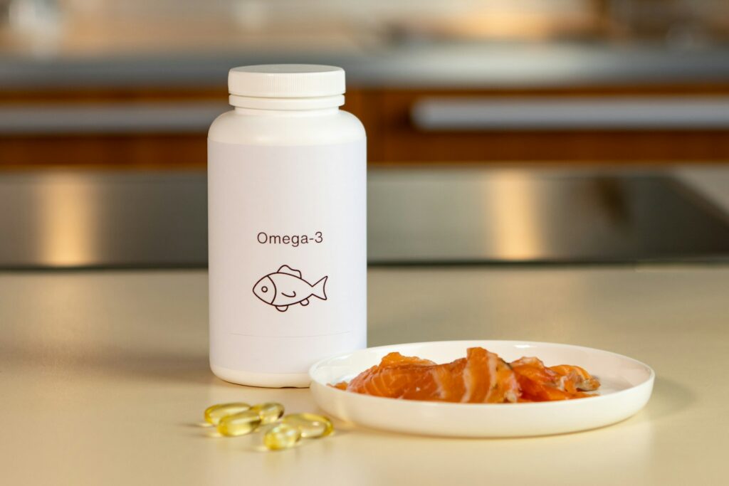Tigela com peixes ao lado de um frasco de suplemento de ômega-3