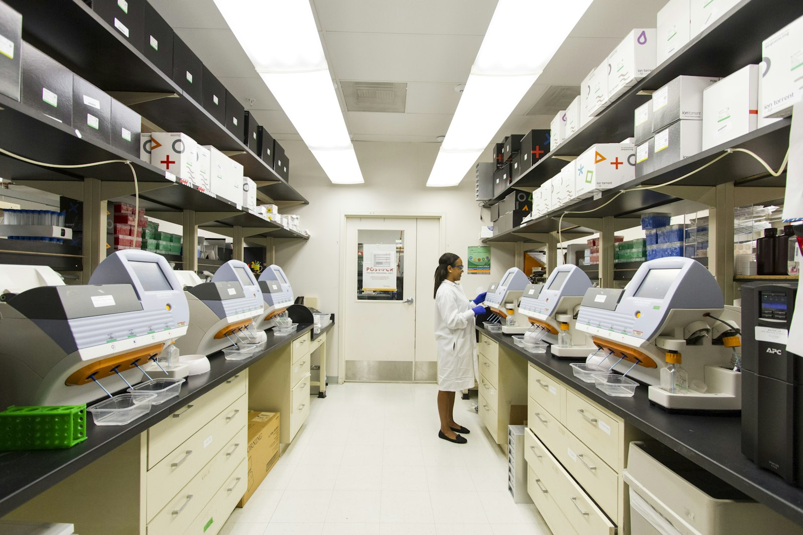 Técnica trabalhando com equipamentos de sequenciamento genético em laboratório de pesquisa